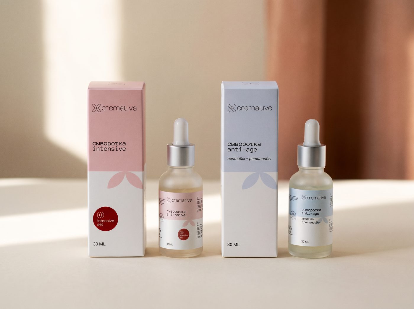 Две сыворотки Cremative — intensive и anti-age — в коробках на светлом фоне