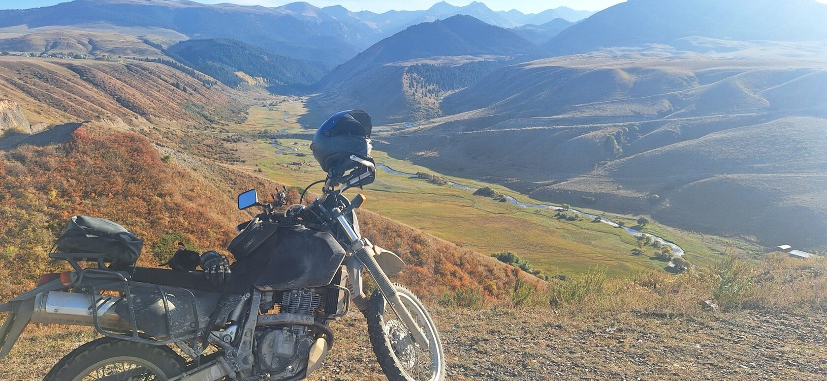 Suzuki DR650SE above a river valley on the road to the Kolsai Lakes