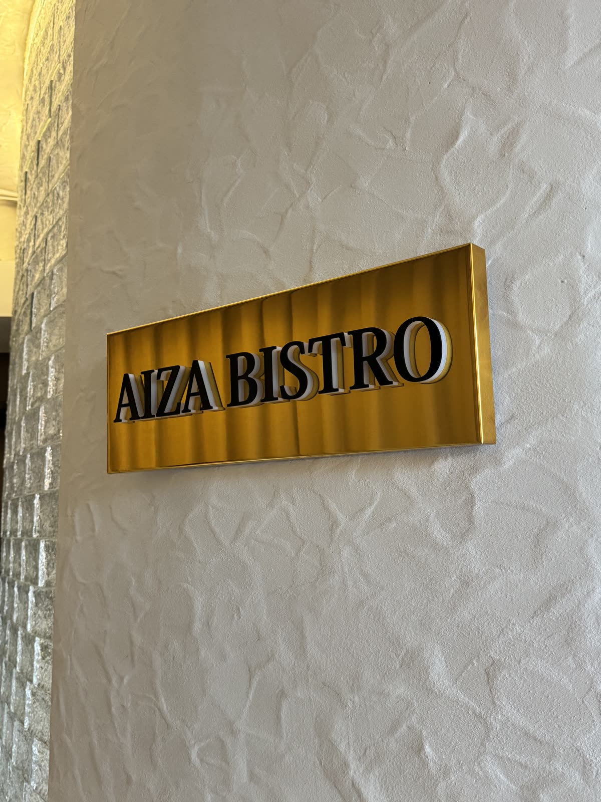 Вывеска AIZA BISTRO — золотой световой короб с объёмными буквами