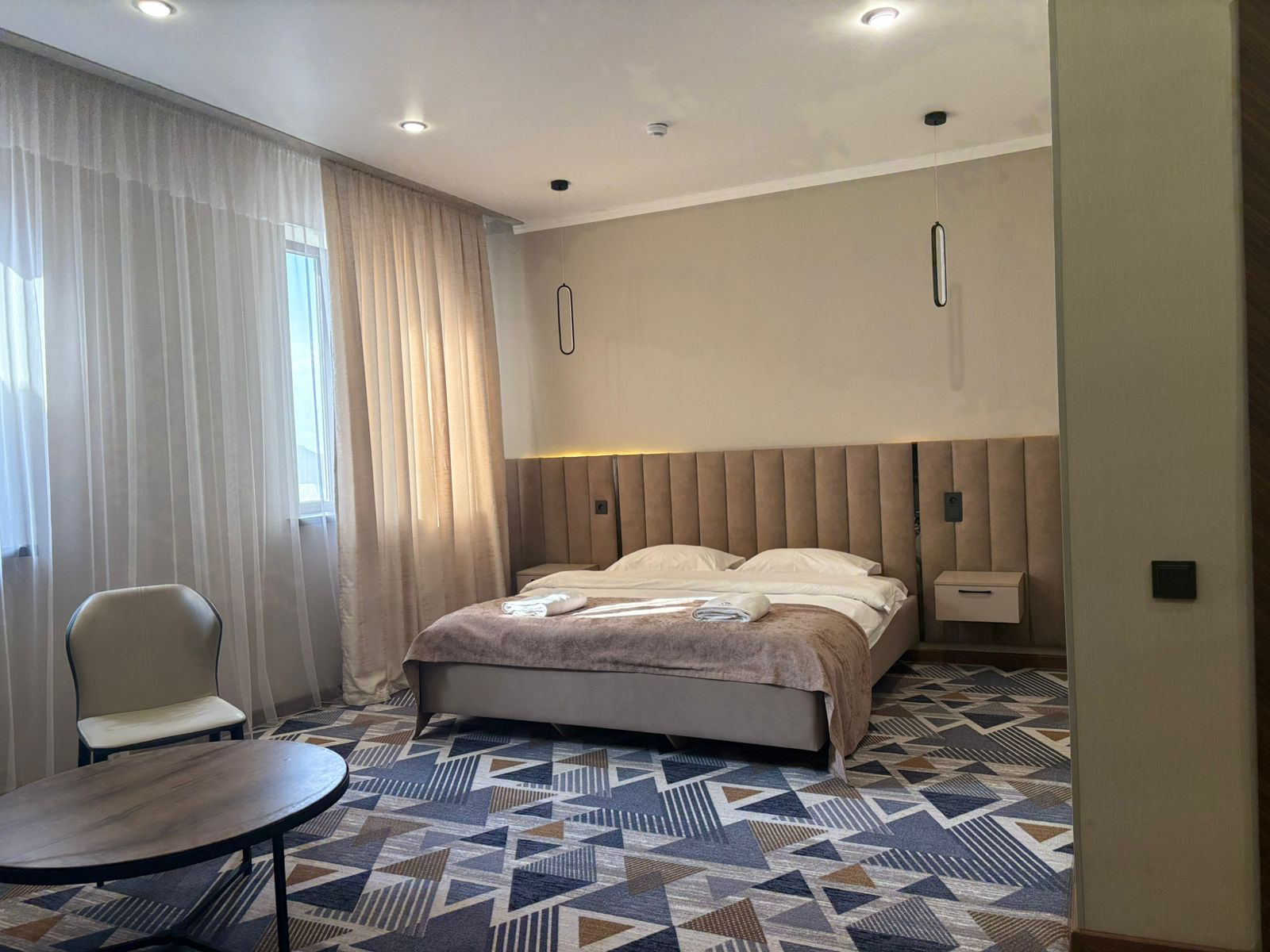 Номер DELUXE в отеле IRIS LUX, Тараз: большая кровать, кресло и столик у окна