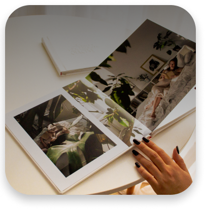 На столе лежит белая фотокнига с красивыми изображениями. Изображения качественные и яркие.