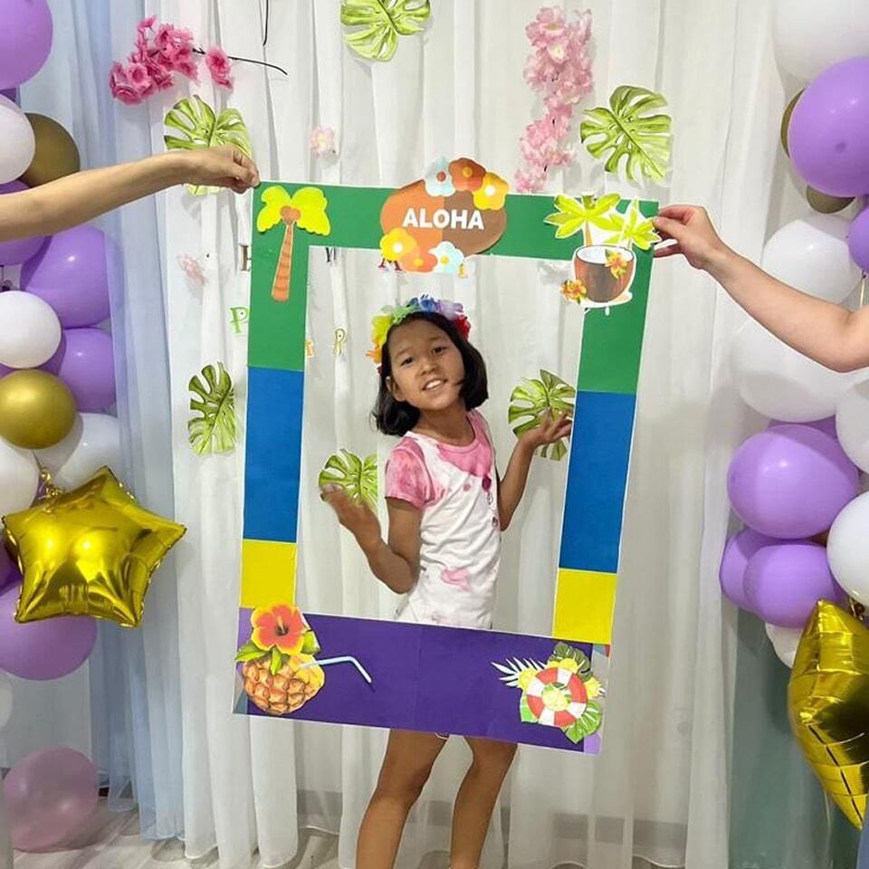 Дети фотографируются на тематической вечеринке в гавайском стиле