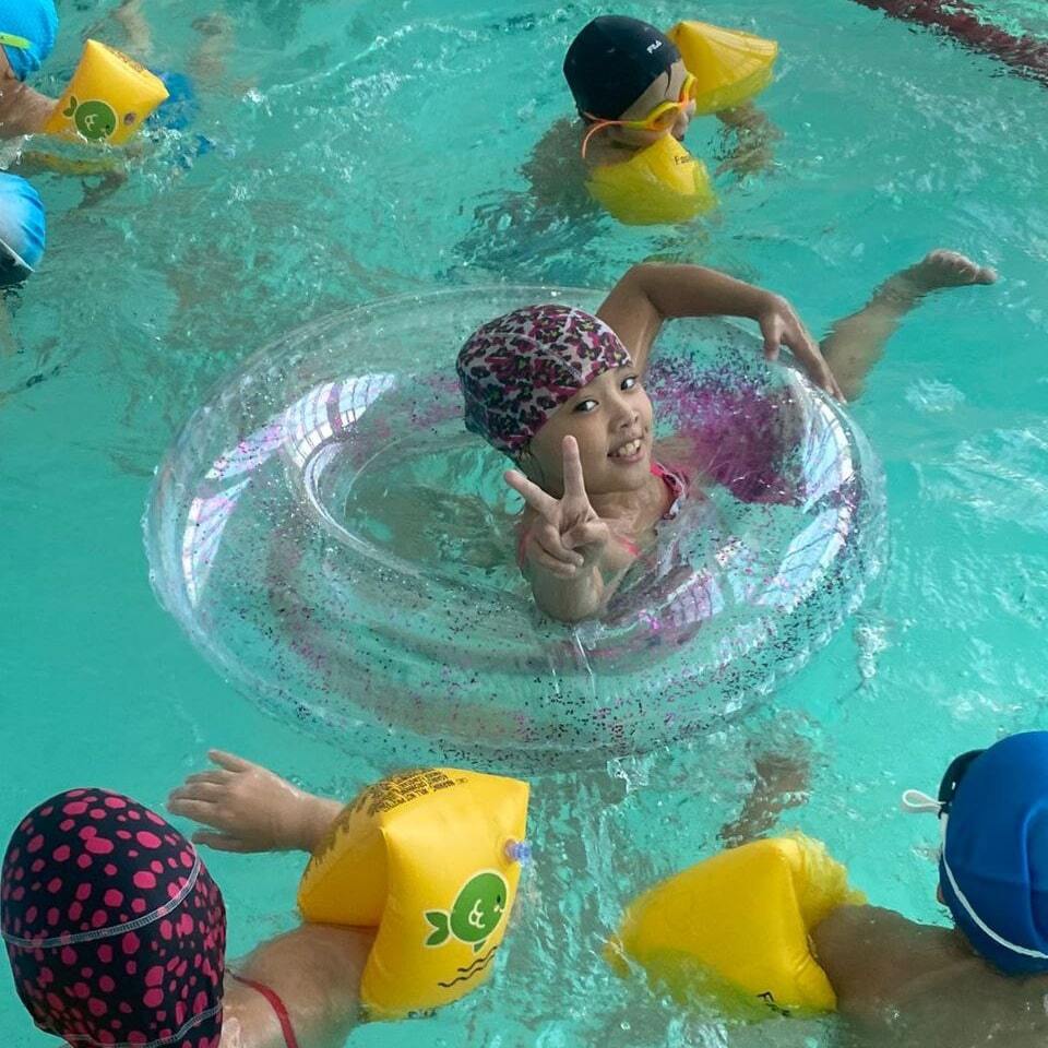 Дети плавают в бассейне с кругом и рукавами