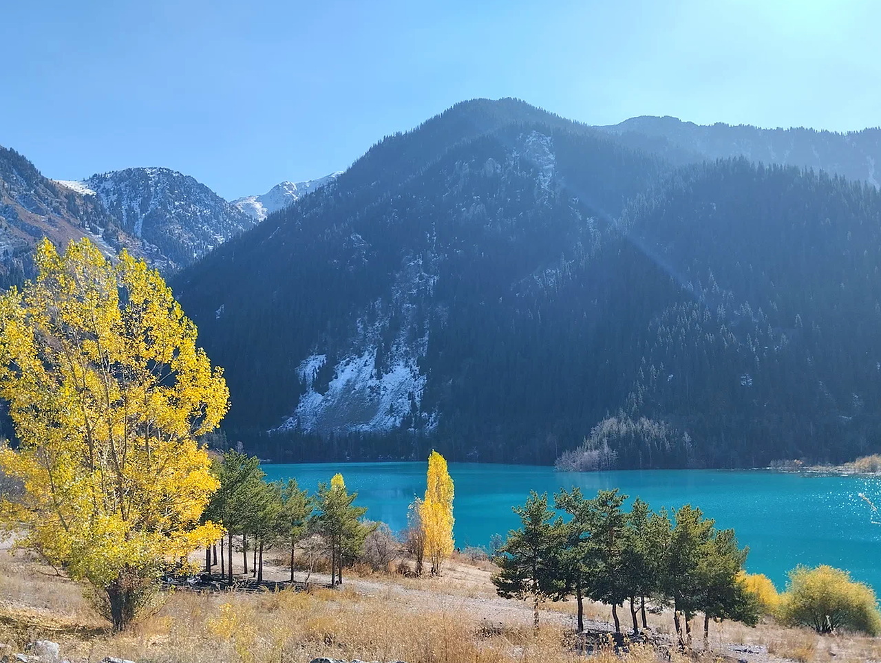 Mountain Issyk Lake surrounded by forested slopes of the Ile Alatau