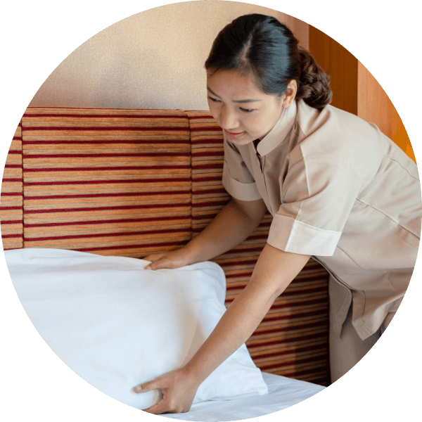 Женщина горничная подправляет постельное белье в гостинице